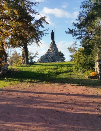 Vue du sanctuaire Notre-Dame de la Roche : une statue de la Vierge Marie au milieu des arbres